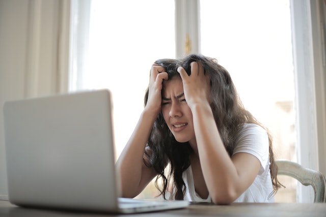 Stressed out person on their laptop trying to figure out what beauty insurance company to use